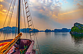 Ha Long Bay, Vietnam. Wide angle landscape view of tourist boat at sunset among the limestone karsts and islets.