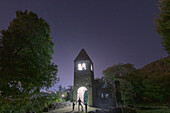 Cheerful man with two little boys sons admiring the illuminated abbey of San Pietro in Vallate, Valtellina, Lombardy, Italy