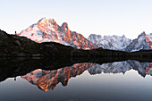 Person steht auf einem Felsen und betrachtet den Sonnenuntergang über den majestätischen Gipfeln des Mont-Blanc-Massivs, Lacs des Cheserys, Haute Savoie, Frankreich