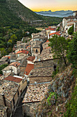 Panorama of a medieval village seen from above with the houses leaning against each other. In the background, the Gran Sasso chain at sunset. Pettorano sul Gizio, province of L'Aquila, Abruzzo, Italy, Europe