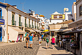 Touristen beim Einkaufen in den Kopfsteinpflasterstraßen der Altstadt von Albufeira, Bezirk Faro, Algarve, Portugal