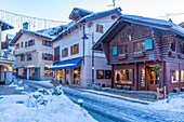 View of shops, town centre and snow covered mountains in Courmayeur at dusk during Christmas, Courmayeur, Aosta Valley, Italian Alps, Italy