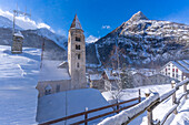 View of snow covered mountains, rooftops and Church of Saint Pantalon in Courmayeur in winter, Courmayeur, Aosta Valley, Italian Alps, Italy
