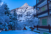 View of chalets and snow covered mountains in Courmayeur before dawn in winter, Courmayeur, Aosta Valley, Italian Alps, Italy