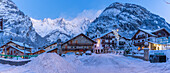 View of chalets and snow covered mountains in Courmayeur before dawn in winter, Courmayeur, Aosta Valley, Italian Alps, Italy