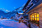 View of chalets and snow covered mountains in Courmayeur before dawn in winter, Courmayeur, Aosta Valley, Italian Alps, Italy