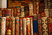 Stacks of vibrant handwoven Moroccan rugs and carpets displayed in a traditional shop in Fes, Morocco