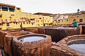 Tannery workers overseeing dye pits in a traditional leather tannery in Fes, Morocco