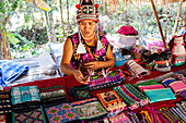 Akha hill tribe woman, originally from Myanmar, selling her handicraft goods in Baan Tong Luang eco village near Chiangmai, Thailand