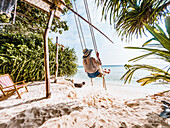 Woman swinging on a tropical beach, summer fun, The Maldives, Indian Ocean