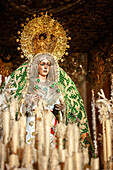 Virgin of Esperanza Macarena on her float surrounded by candles during the solemn conclusion of Good Friday procession in Seville.