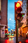 Blurred evening city street with a red traffic light and bokeh reflections.