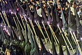 Seville, Spain, Apr 9 2009, Nazarenos from Gran Poder carry candles as they march through a narrow street filled with onlookers during Holy Week in Seville.