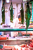 Hanging game animals in a butcher shop with a traditional and rustic ambiance.