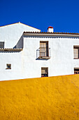 Traditional architecture with a vibrant yellow and white exterior under blue sky.