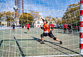 Seville, Spain, Nov 9 2024, Youth playing futsal outdoors under the bright sun in a scenic Seville location.