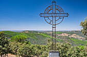 Iron cross at the summit of Tentudía mountain ridge offers panoramic views of the surrounding green hills in Badajoz, Extremadura.