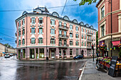 Historic buildings line Hegdehaugsveien in Oslo, showcasing vibrant styles under a cloudy sky. A car and bicycle are parked nearby.