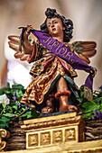 An angel holds a purple ribbon embroidered with 'Amor' on the float of Cristo del Amor, celebrating love and devotion in Seville.
