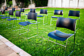 An arrangement of empty chairs on a green grass field for an outdoor event.