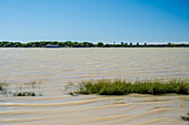 A scenic boat glides along the Guadalquivir River near its mouth in Sanlucar de Barrameda, showcasing the natural beauty of Andalusia.