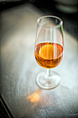 A delicately filled glass of amontillado sherry wine on a reflective background.