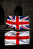 Union Jack und St. George's Cross Flaggen im Freien vor einem historischen Gebäude.