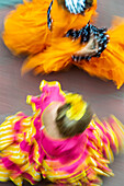 Flowing figures of women in colorful flamenco dresses move gracefully toward the Feria in Seville, captured with long exposure for motion.