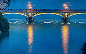 Illuminated Triana Bridge spanning the calm river reflecting the city lights at dusk