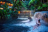 Heiße Quellen aus dem Arenal Vocano im Tabacón Grand Spa, Costa Rica. Ein Besucher genießt einen der warmen Bäche, die durch das Tabacon Hot Spring Resort and Spa in Costa Rica fließen