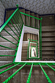 An artistic green staircase with a white backdrop, patterned tiles, and a parked bicycle.
