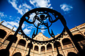 Eisenverzierung an einem Brunnen im Hof des Fonseca-Kollegs unter strahlend blauem Himmel in Salamanca.