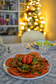 A beautifully arranged table for a Christmas meal features vibrant dishes and decorative accents amidst soft, glowing lights.