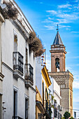 San Marcos Church tower rises above colorful buildings along San Luis street on a clear day in Seville, highlighting the city’s charm.