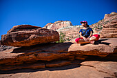 Junge kaukasische Frau sitzt mit gekreuzten Beinen auf dem Canyon Overlook Trail im Zion National Park, Utah