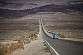 Silver Airstream camper travel trailer on an empty road in the area of Death Valley, California