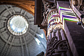 Colorful stained glass filters through the Church of El Salvador, highlighting a Baroque column during Holy Week in Seville, Andalusia.