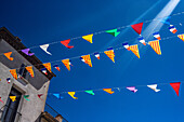Vibrant flags of Catalonia and France and in various colors wave in the air above a building in Prades, capturing festive spirit in Languedoc-Roussillon.