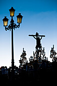 Die Silhouette des Cristo del Cachorro ist auf seinem Wagen zu sehen, der während der Karwoche in Sevilla, Andalusien, die Triana-Brücke überquert.
