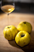 Ein Glas Wein, gepaart mit Quitten, dargestellt in einer stimmungsvollen, künstlerischen Komposition.