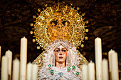 Virgen de la Esperanza Macarena prepares for the solemn Good Friday procession, surrounded by glowing candles in Seville, Andalusia.
