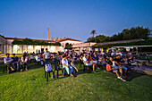 Seville, Spain, July 26 2022, Visitors enjoy a summer concert in the gardens of CAAC, surrounded by historic architecture and a serene evening atmosphere.