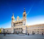 Blick auf die Fassade der Almudena-Kathedrale unter strahlend blauem Himmel in Madrid, Spanien