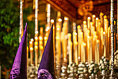 During Holy Week in Seville, penitents stand before the Virgin of Victory’s canopy, surrounded by glowing devotional candles.