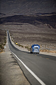 Silver Airstream camper travel trailer on an empty road in the area of Death Valley, California