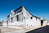 Whitewashed winery walls in the Barrio Alto area exhibit traditional architecture under a bright blue sky in Sanlucar de Barrameda.