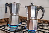 Two metal coffee makers on a stove in Carratraca, Malaga, Spain kitchen