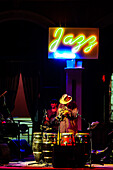 Sanlucar de Barrameda, Spain, Jul 17 2004, Jerry Gonzalez performing with trumpet and percussion under vibrant neon lighting in a venue.