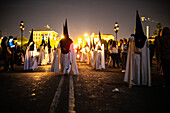 Nazarenos from the Estrella brotherhood walk with candles in the night of Palm Sunday, celebrating Holy Week in Seville.