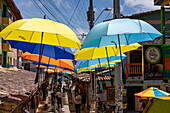 Colorful parasols provide shade on the Plazoleta de los Zócalos, a shopping street in Guatape, Colombia.